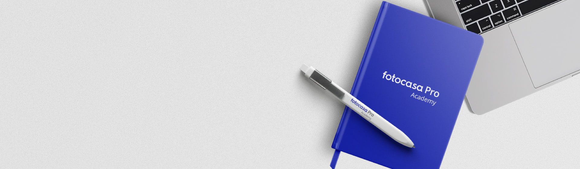 Libreta y boli de Fotocasa Academy sobre una mesa con un portátil