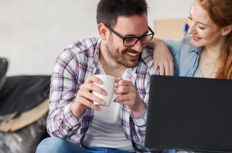 Pareja mirando un portátil y sonriendo