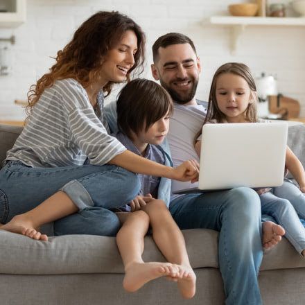 Família sentada en un sofá, mirando un portátil