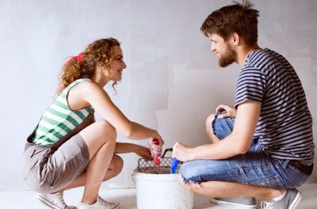 Chico y chica preparados para pintar una pared de una habitación