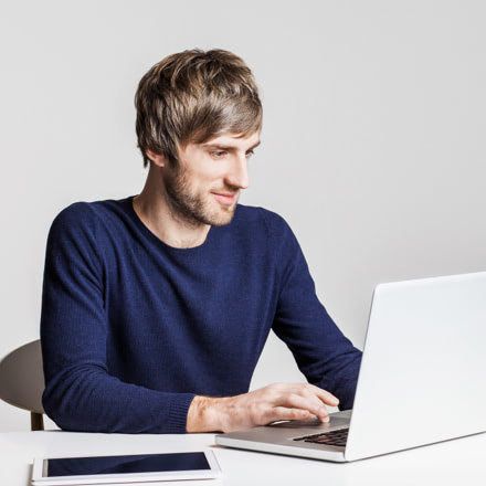 Chico sentado mirando su portátil