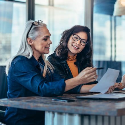 Dos mujeres comentando los datos de un informe frente a un portátil