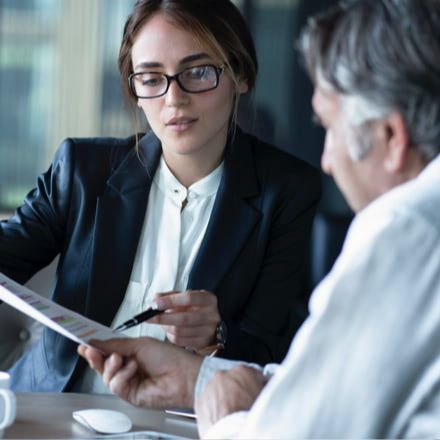 Dos hombres comentando los datos de un gráfico, sentados en una mesa reunión